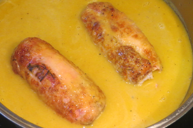 rollitos de pollo rellenos acabándose de cocer en la salsa