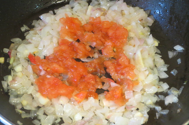 añadiendo el tomate a la cebolla y al ajo