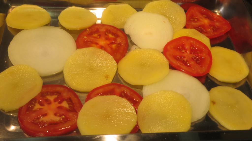 patatas, cebollas y tomates en la fuente del horno