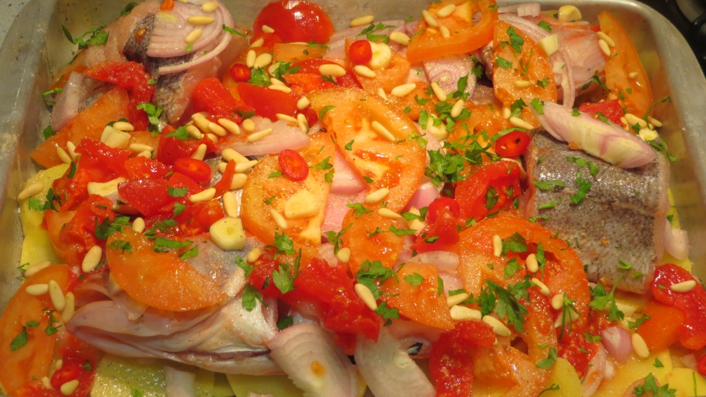 piñones, ajos, guindilla y perejil sobre los tomates y pescados
