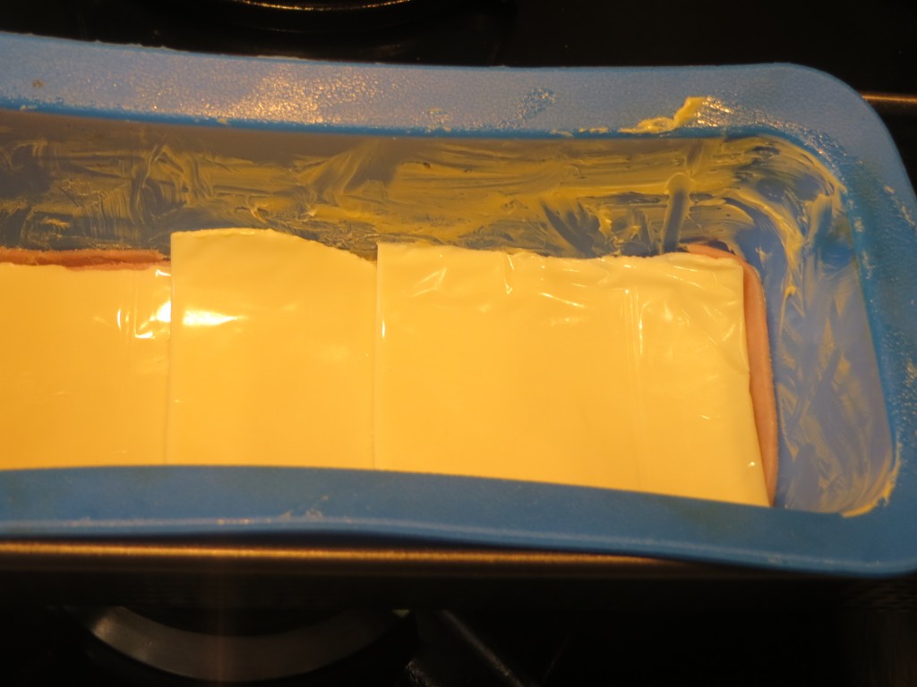 capas de jamón york y queso en el interior del molde 